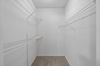 Empty walk-in closet with white shelves and carpeted floor. at Somerset Oaks Apartment Homes, Olathe 66062